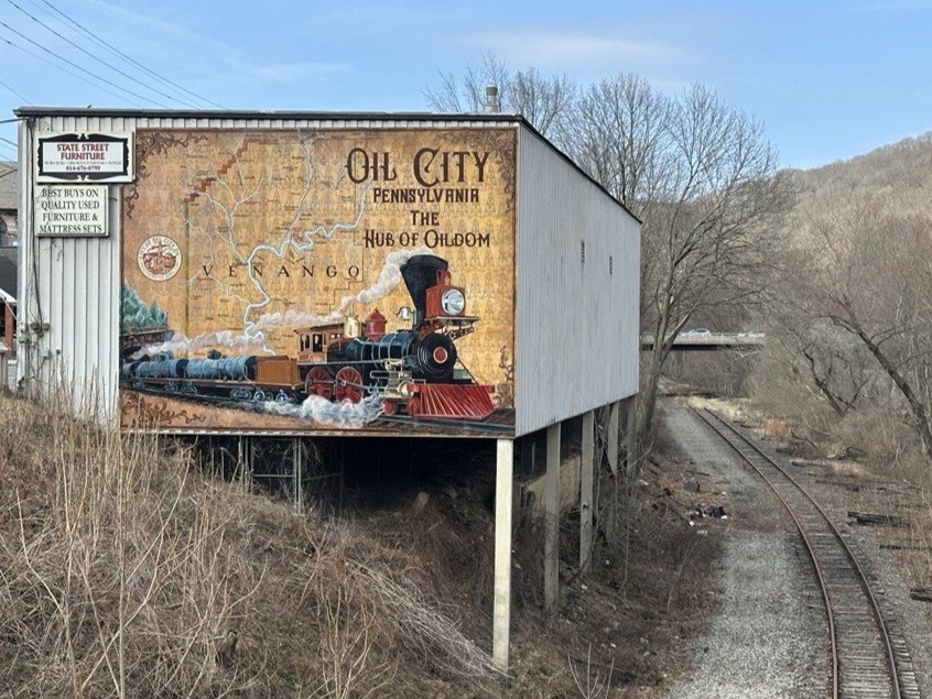 Mural in Oil City, PA that shows the transportation of oil outside the region over time.
