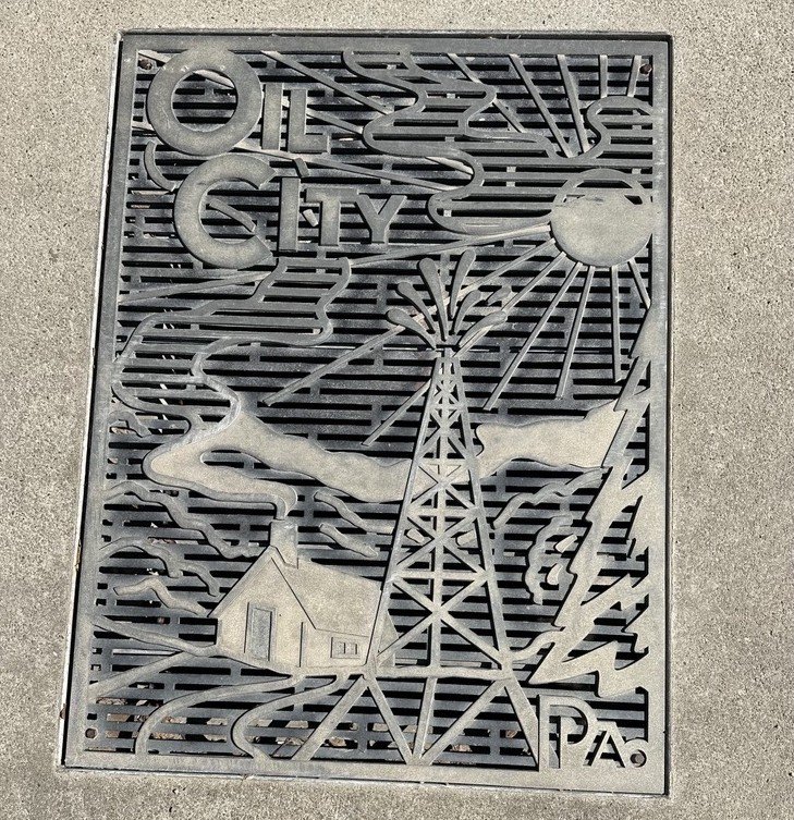 Oil City, PA storm drain adorned with derricks gushing oil