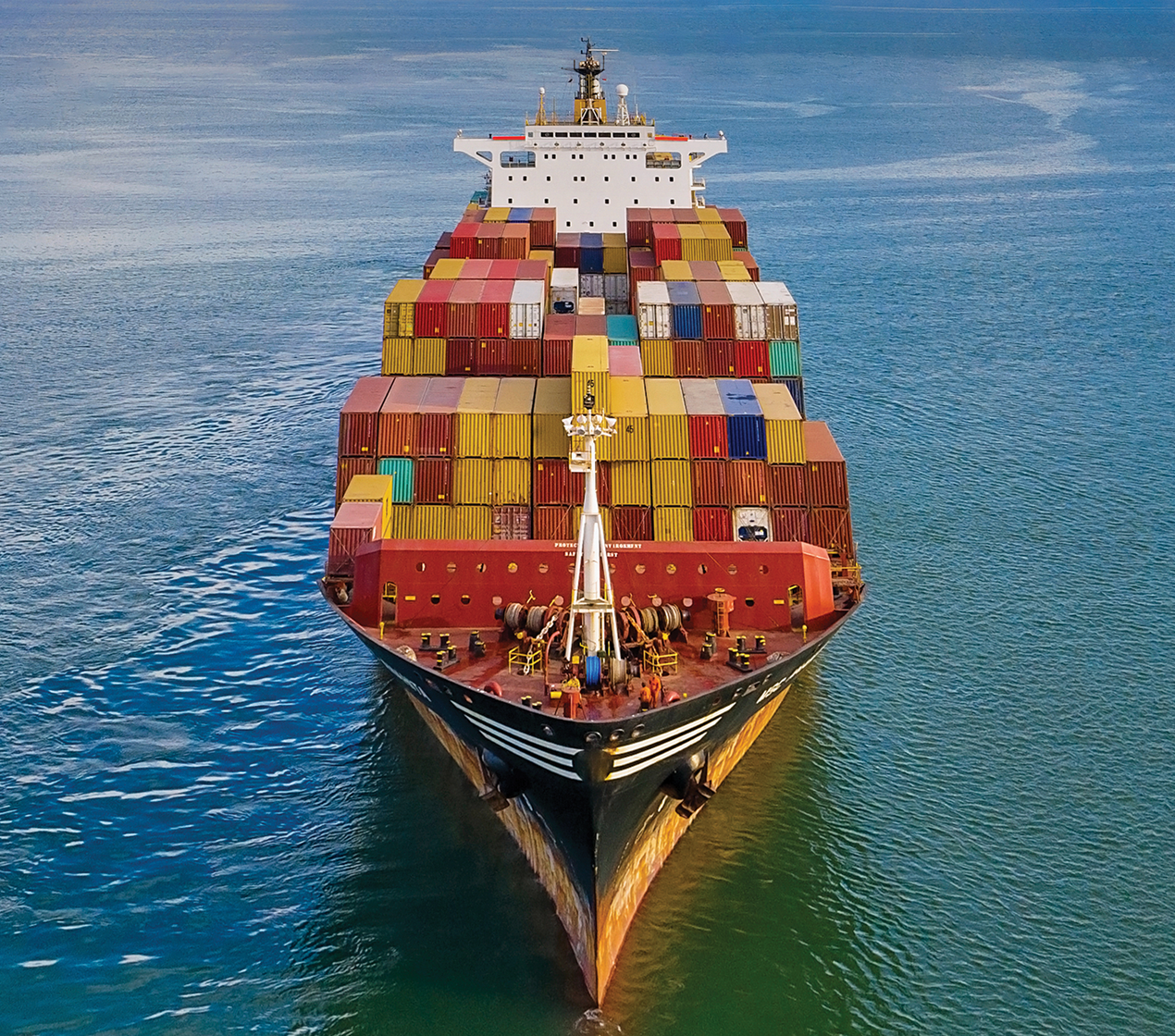 A freight full of shipping containers in the ocean on a sunny day
