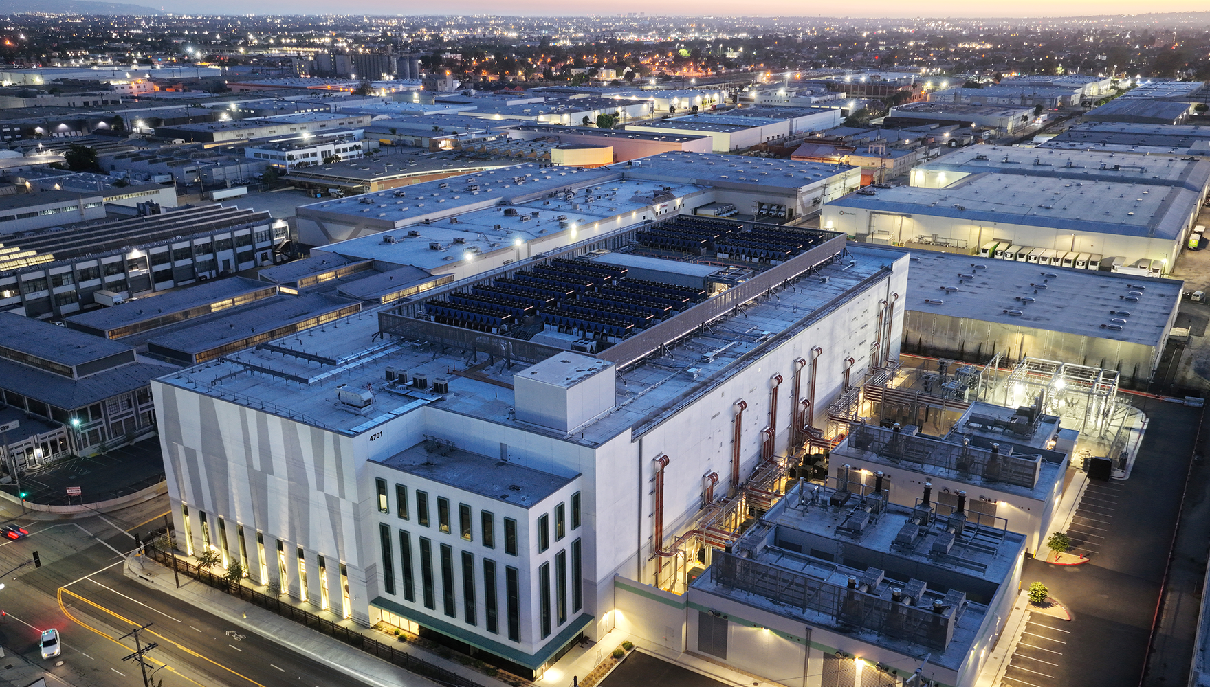 A large data center at dusk with a surrounding community in the background