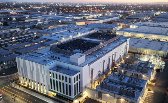 A large data center at dusk with a surrounding community in the background