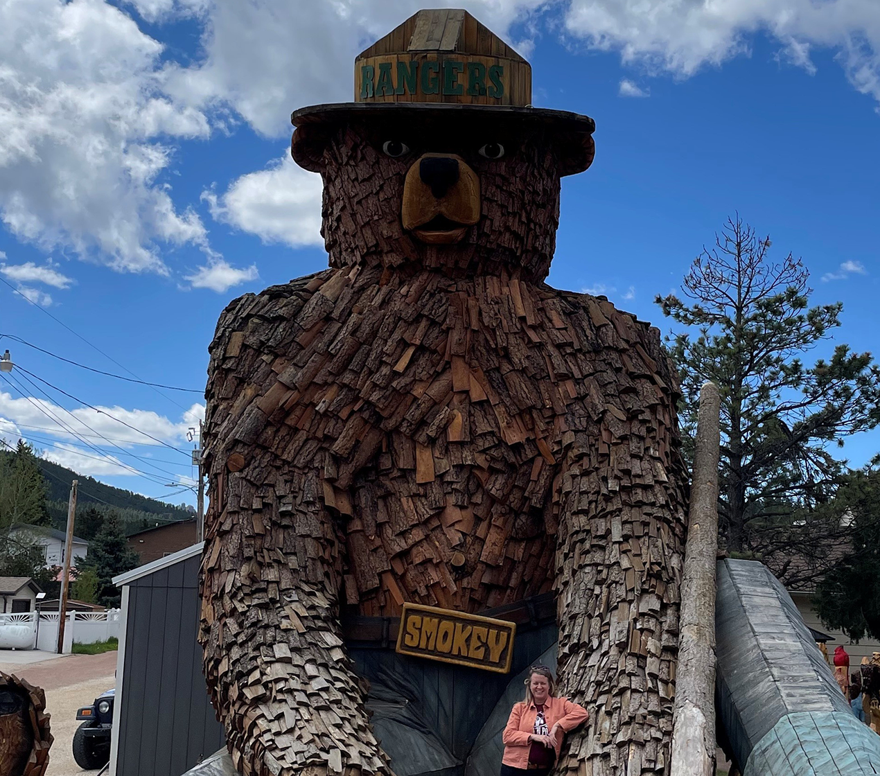 Woman posing next to a large wooden bear