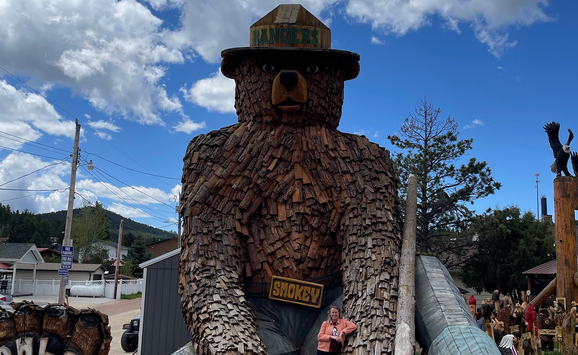 Woman posing next to a large wooden bear