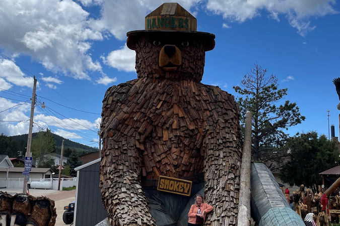 Woman posing next to a large wooden bear