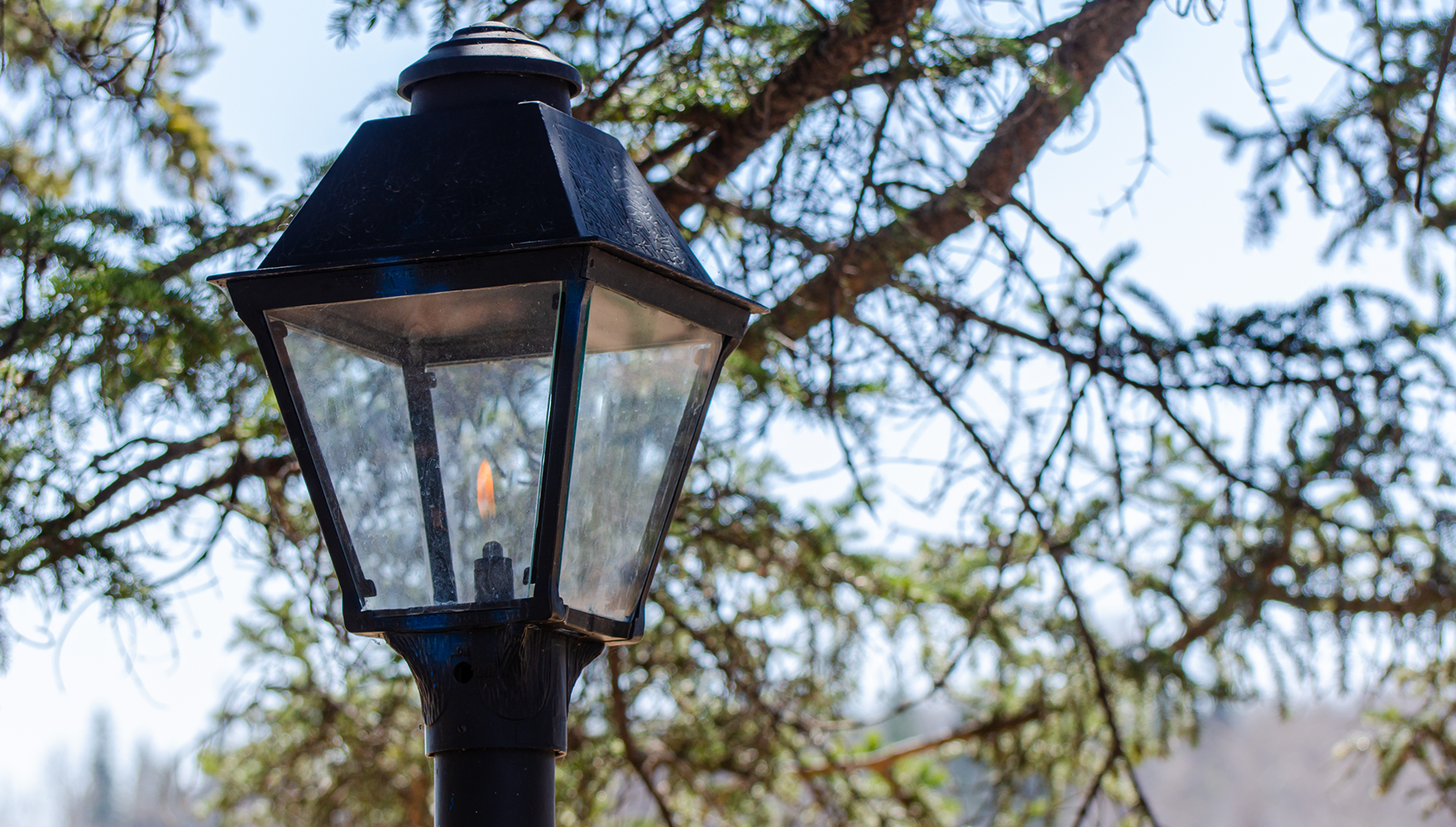 A close-up of a gas streetlight with its flame lit