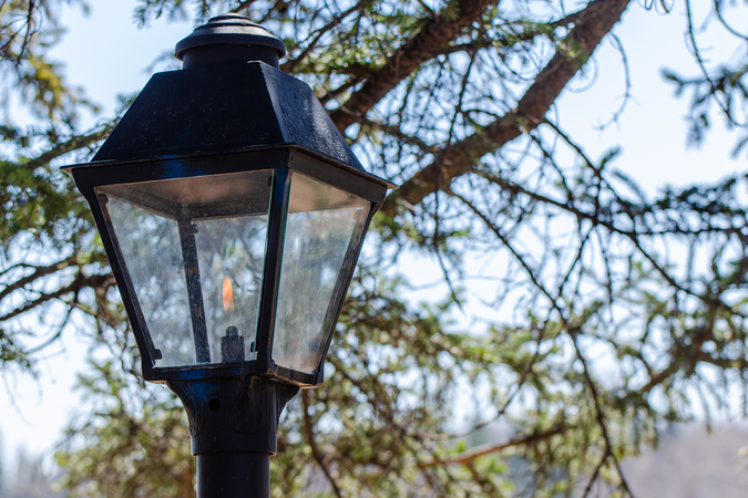 A close-up of a gas streetlight with its flame lit