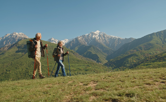 Couple hiking on grassy mountain tops on a sunny day.