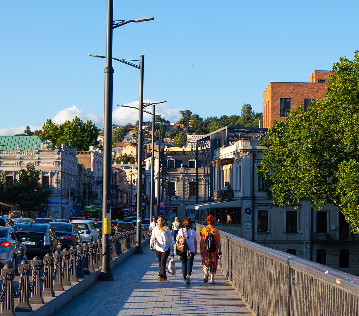Pedestrians cross a bridge alongside cars backed up from traffic