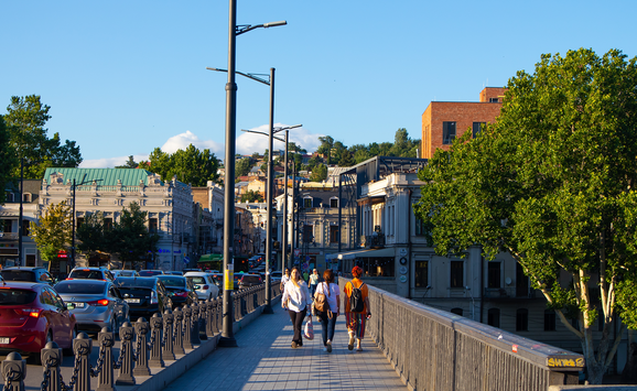 Pedestrians cross a bridge alongside cars backed up from traffic