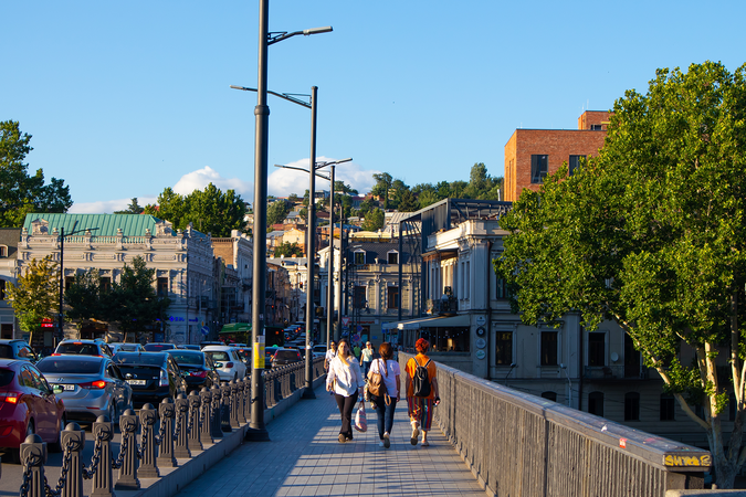 Pedestrians cross a bridge alongside cars backed up from traffic