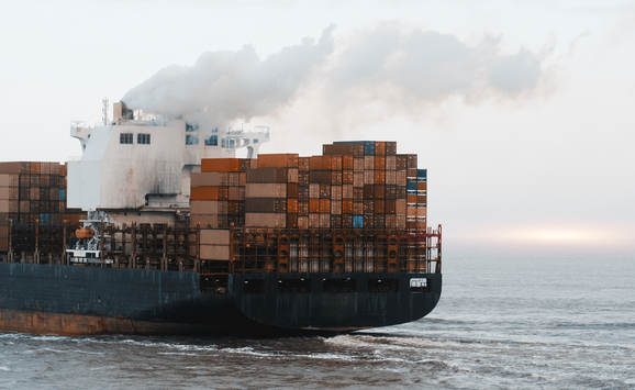 Cargo ship emitting smoke from its chimney.