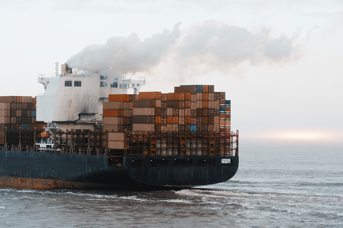 Cargo ship emitting smoke from its chimney.