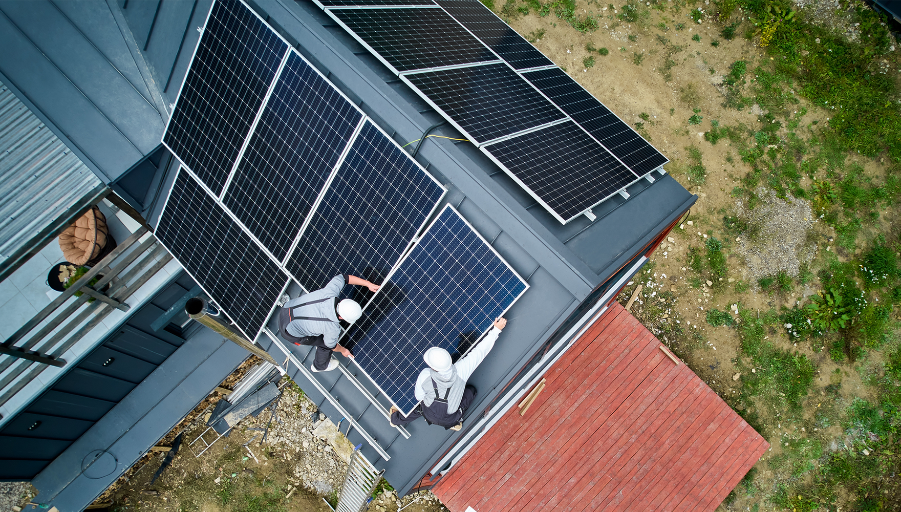 An aerial view of workers installing a solar array on a house roof