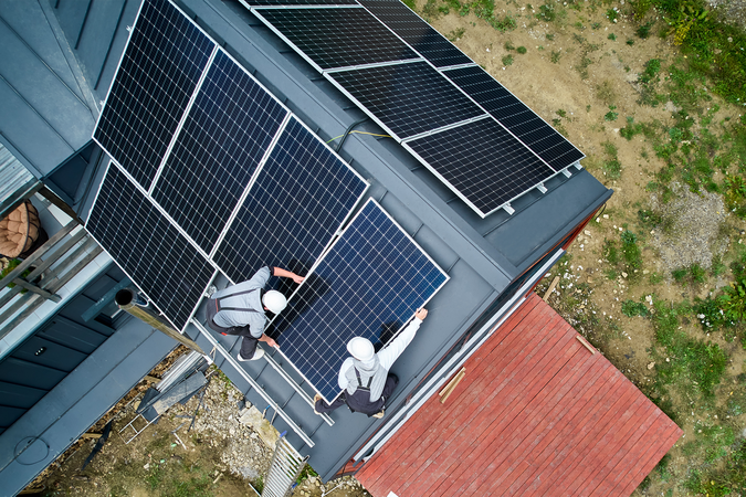 An aerial view of workers installing a solar array on a house roof