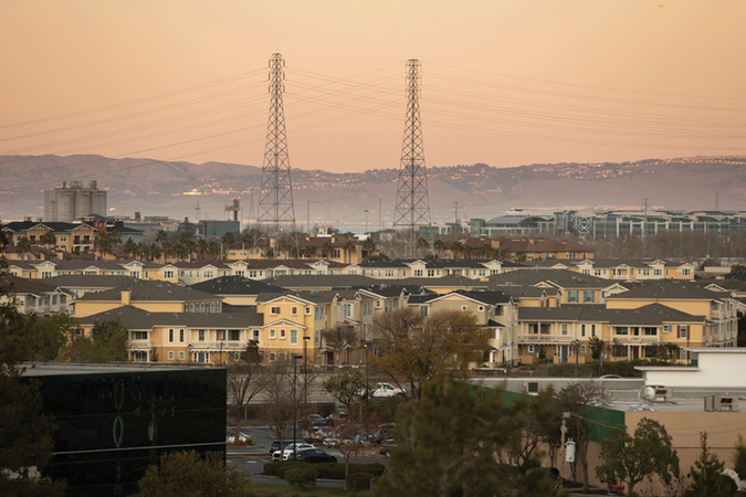 Sunset view of a dense housing neighborhood of Redwood City, California, USA, with electrical transmission towers in the background