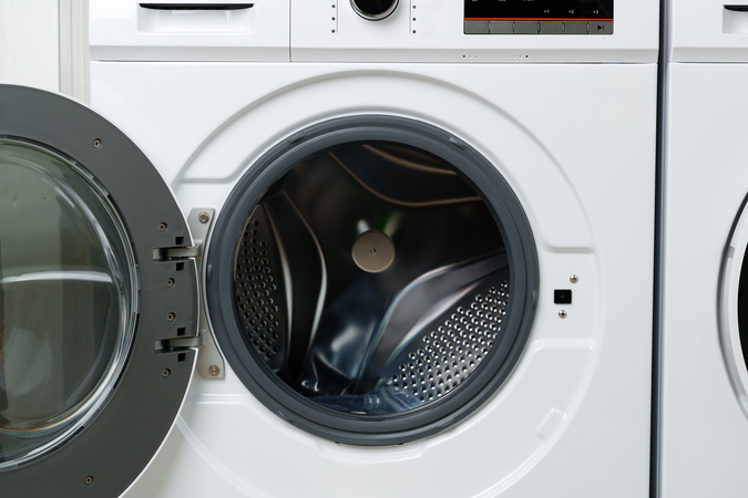 A closeup image of a white front-loading clothes washing machine.
