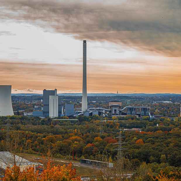 A photo of an industrial area in the fall, with a fossil fuel plant in the center