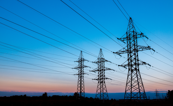 Three high-voltage power lines against a blue and orange sunset.